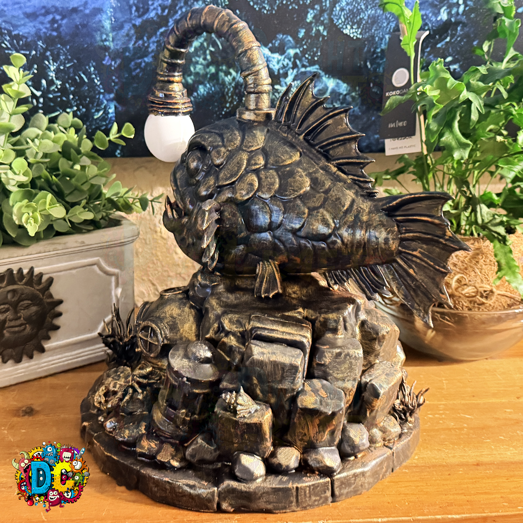 Decorative ambient lighting angler fish sculpture on a rocky base with plants in the background