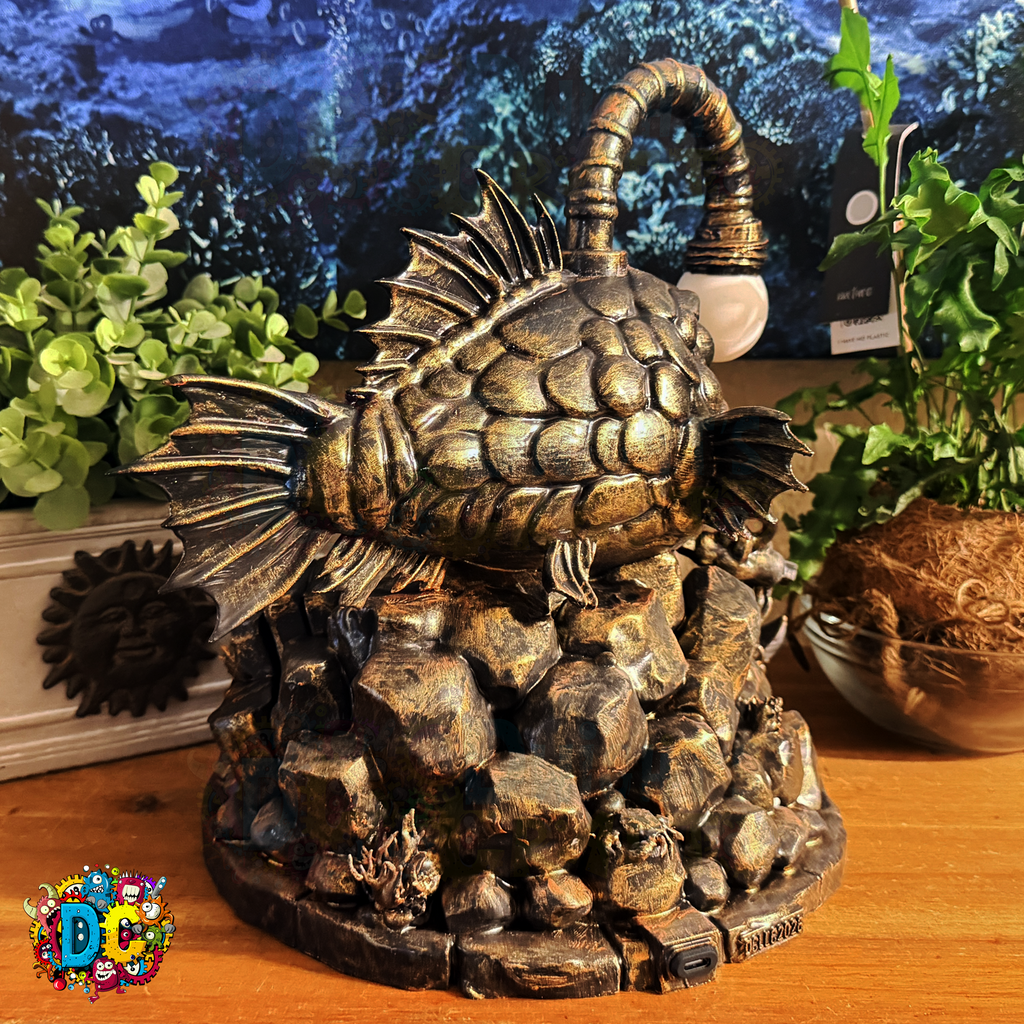 Decorative fish sculpture on rocks with plants in the background