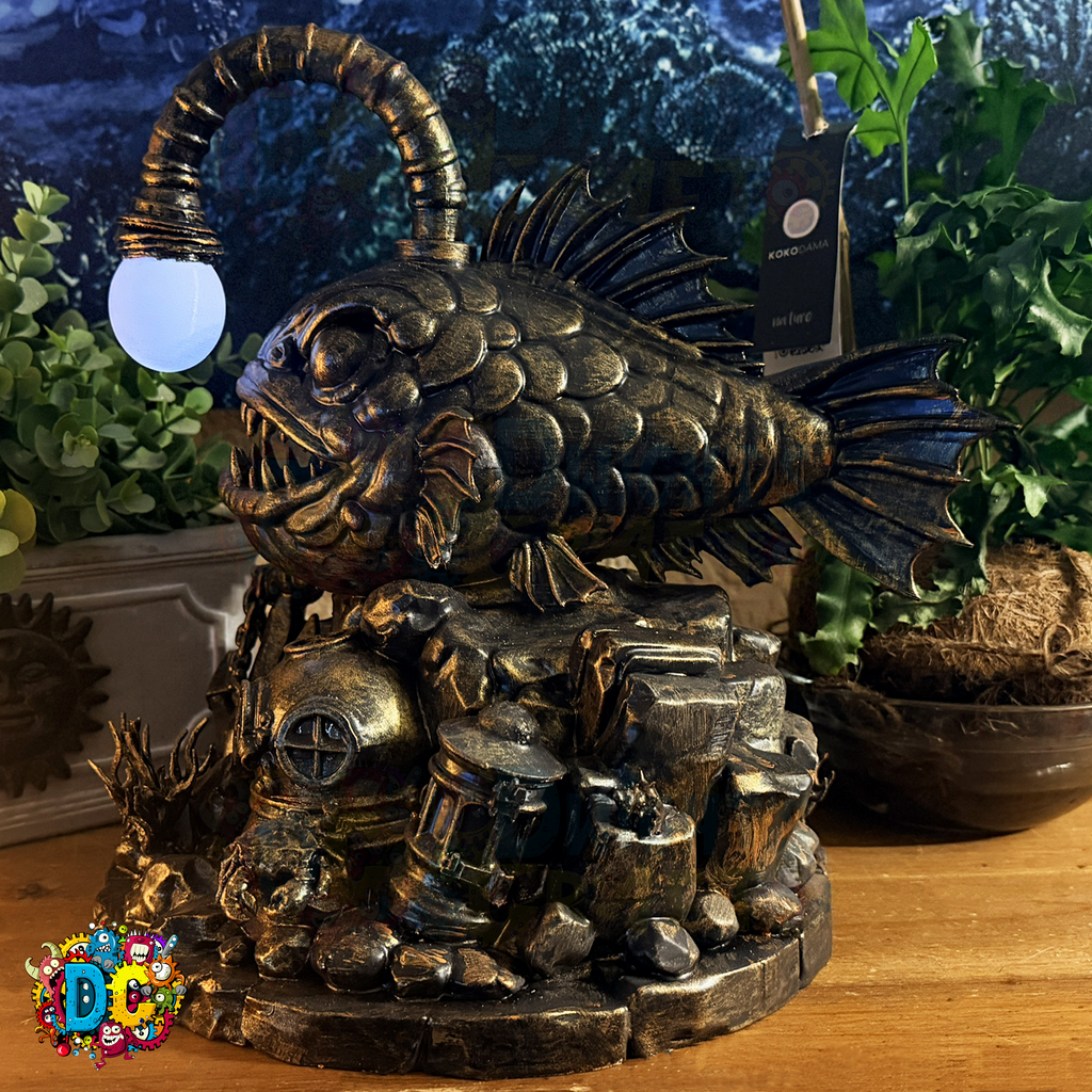 Decorative angler fish sculpture with ambient lighting on a wooden surface with plants in the background