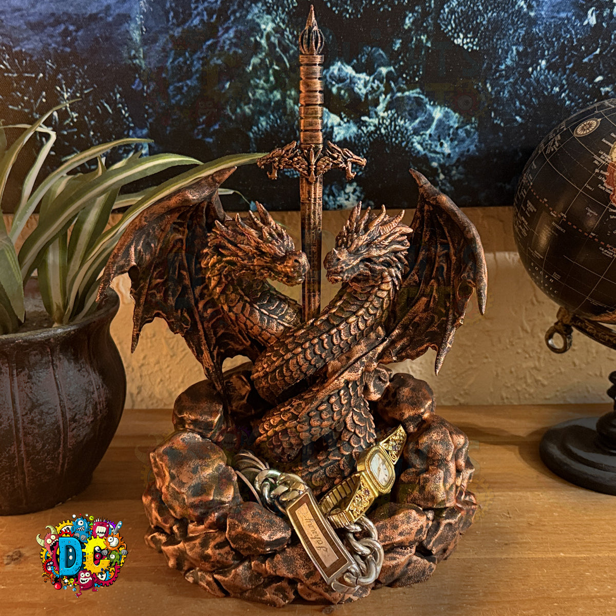 Decorative dragon sculpture with a sword on a wooden surface, next to a plant and globe.