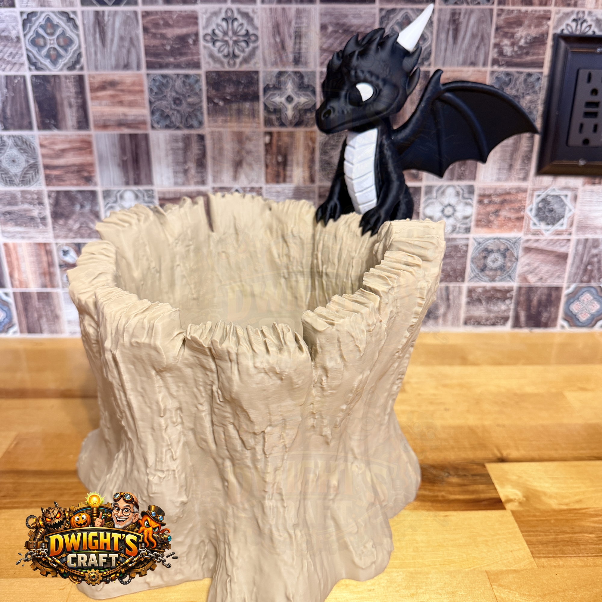 A fantasy tabletop decor piece featuring a black dragon with white horns and wings perched on a textured beige stone-like pedestal, set on a wooden countertop in front of a tiled backsplash. A 'Dwight's Craft' logo is visible in the bottom-left corner.