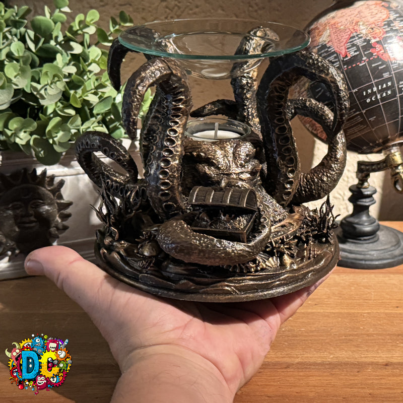 Decorative metal candle holder with snakes held by a hand on a wooden surface.