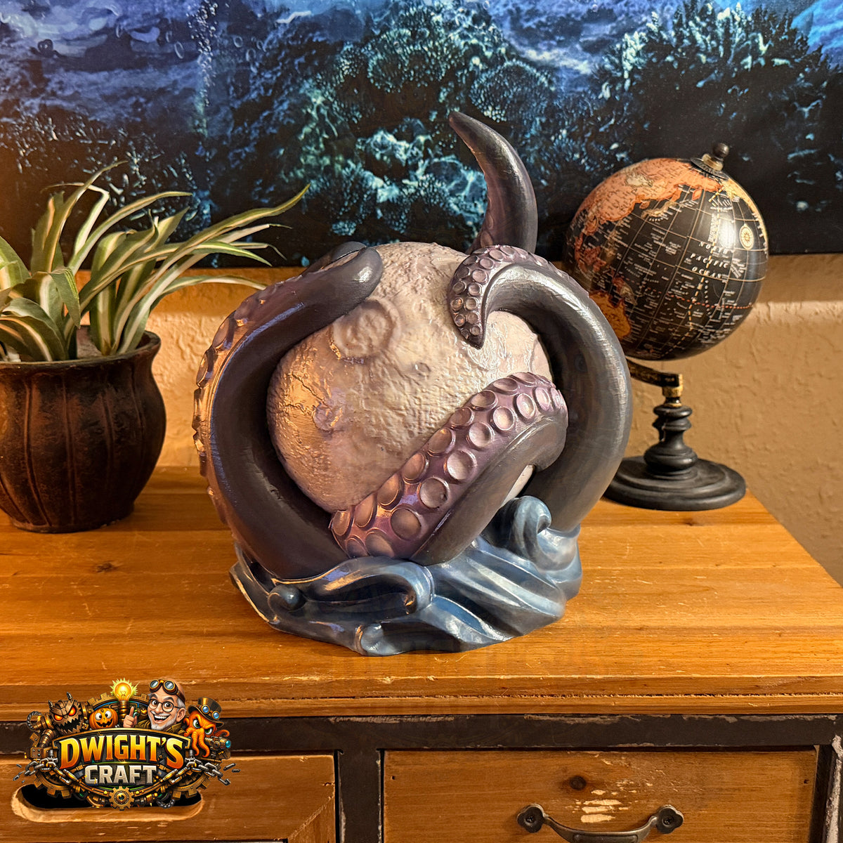 A fantasy octopus sculpture cradling a large pearl-like sphere, displayed on a wooden cabinet alongside a potted plant and a globe. The octopus has dark gray arms with purple suction cups and a blue wave-like base.