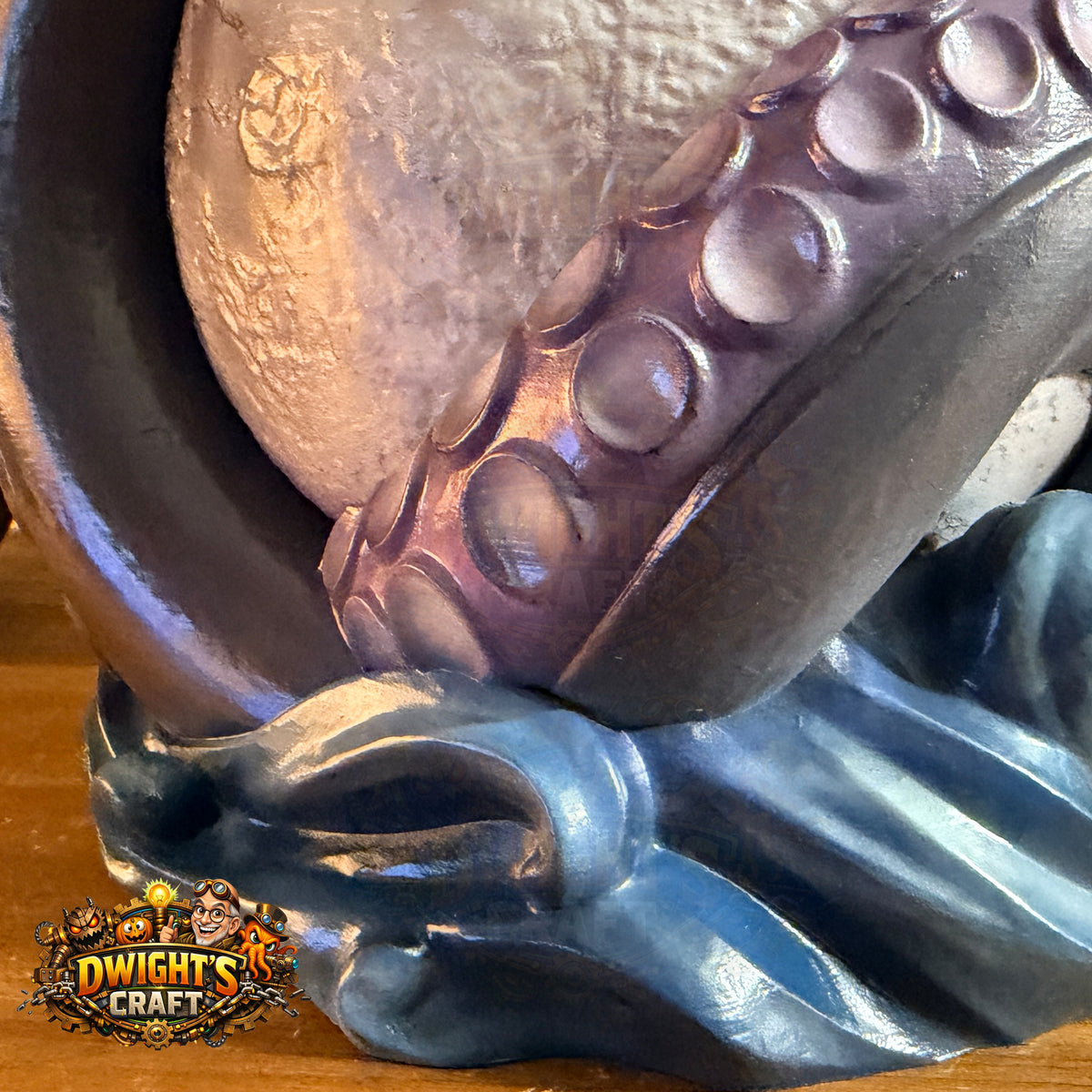 Close-up of a fantasy figurine or decorative sculpture showing a dark purple octopus tentacle gripping a metallic silver sphere, mounted on a blue wave-like base. A 'Dwight's Craft' logo is visible in the lower-left corner.