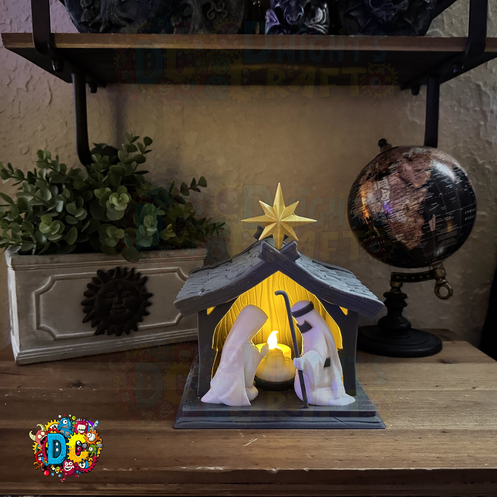 Decorative nativity scene with a star on top, placed on a wooden surface with a plant and globe in the background.