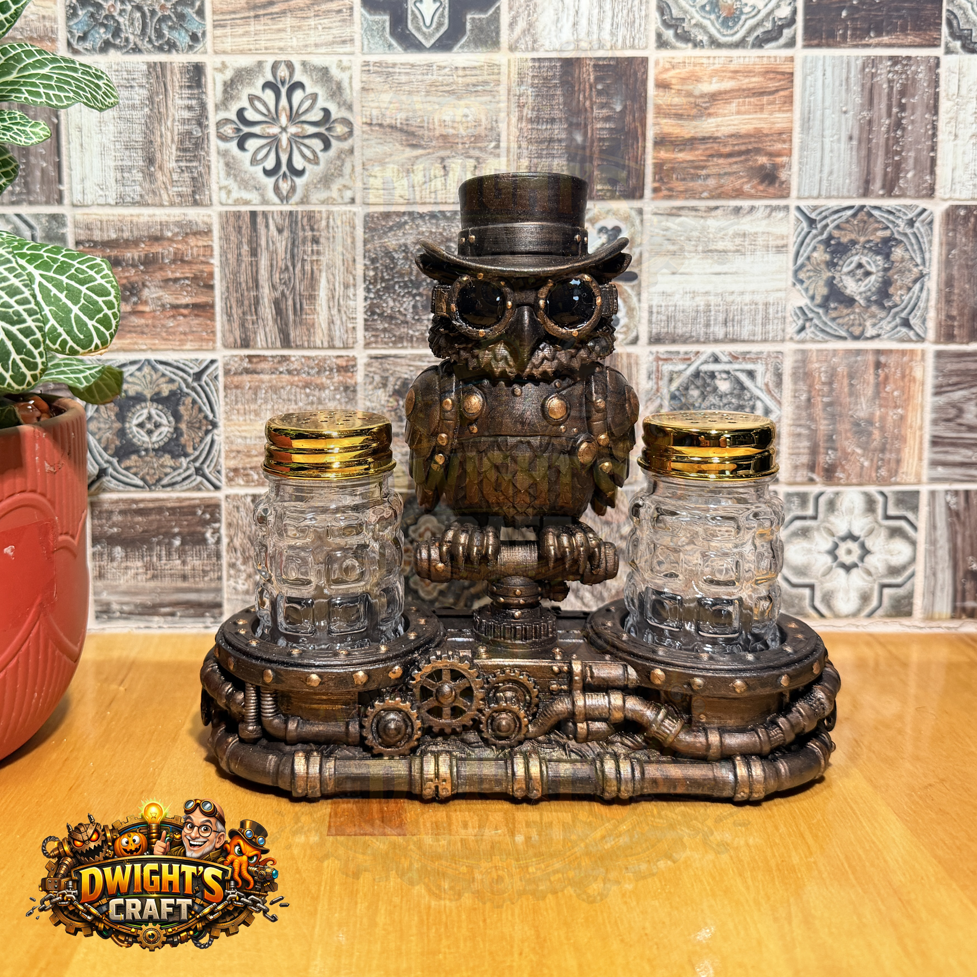 Steampunk owl centerpiece with two clear glass mason jars on a decorative metal base, displayed on a wooden surface against a tiled backsplash. A plant pot is visible at left, and a 'Dwight's Craft' logo appears in the lower-left corner.