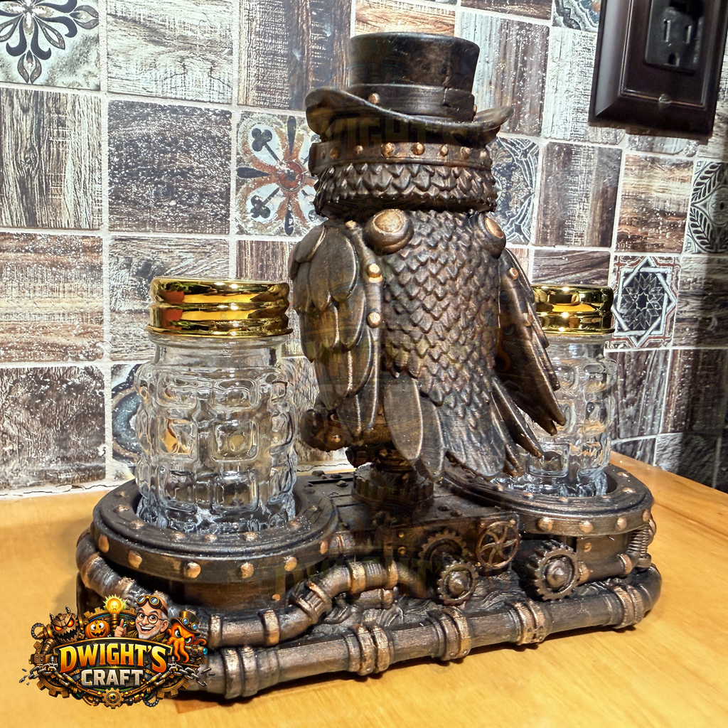 Steampunk owl figurine in dark bronze metal with a top hat and goggles, perched on a pipe-like base with two clear glass mason jar candle holders on either side, shown on a wooden tabletop against a tiled wall. A 'Dwight's Craft' logo is visible in the lower-left corner.